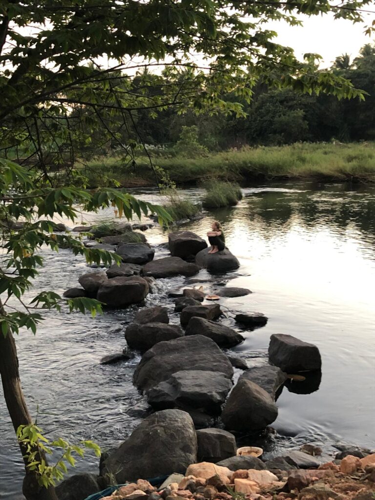 Young girl sitting on rock in river Cauvery