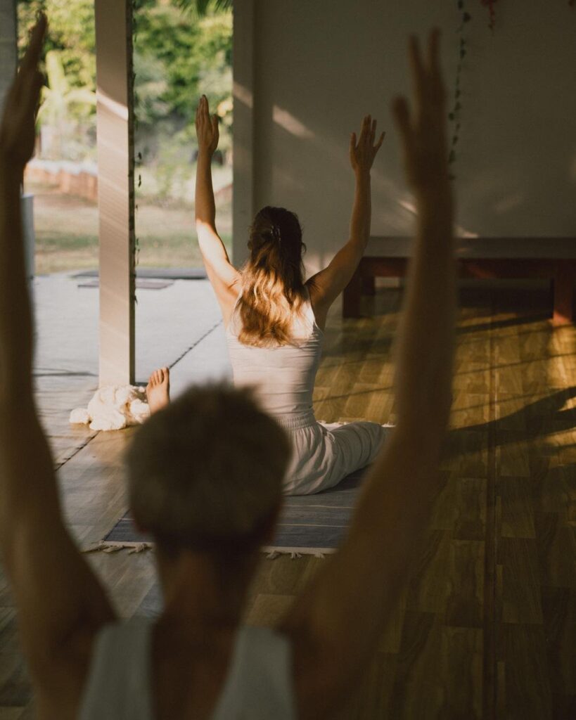 Yoga practitioner with arms raised during asana practice at Yoga Gita Ashram